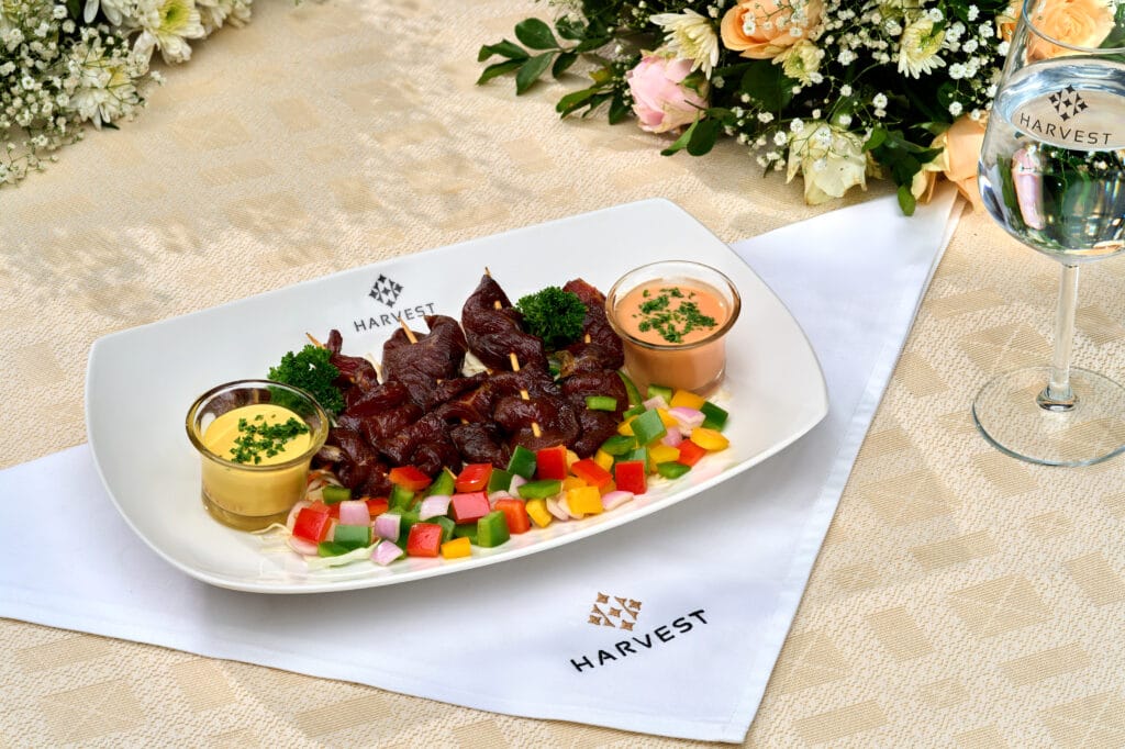 Harvest Caterers Kochi offering grilled tender beef strips with sauces and peppers.