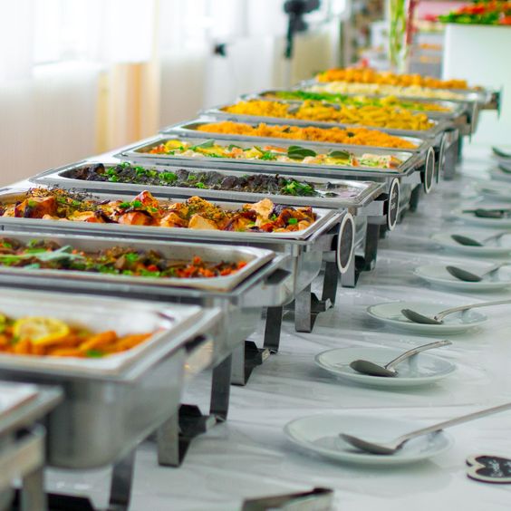 A neatly arranged buffet line with a variety of hot dishes in chafing trays, representing diverse wedding catering styles.