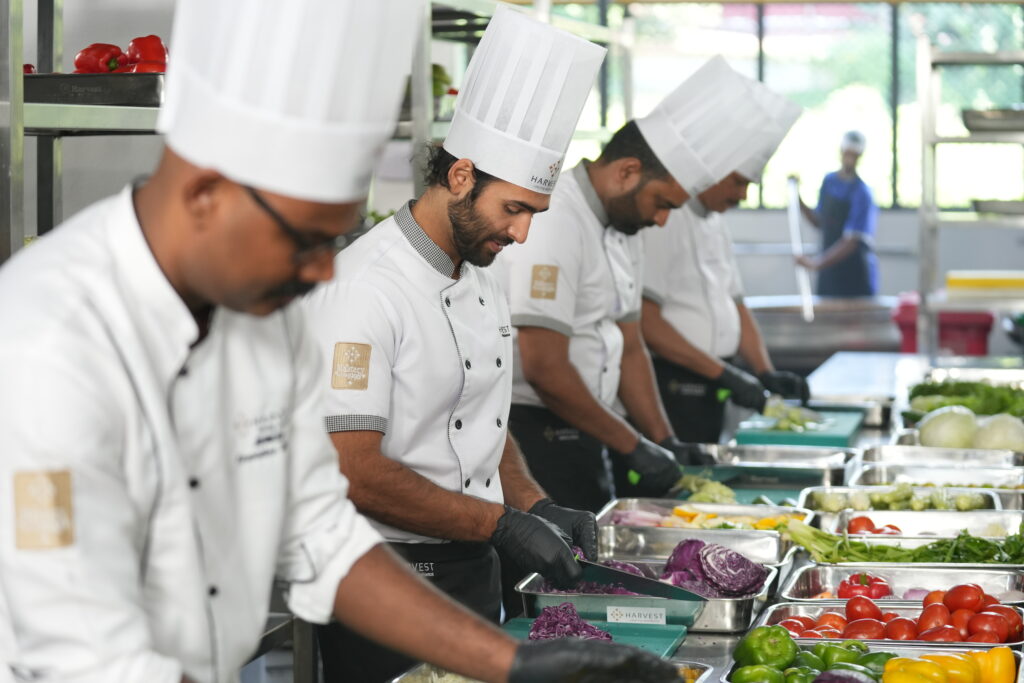 Professional chefs preparing fresh vegetables in a commercial kitchen as part of premium wedding catering in Kochi.