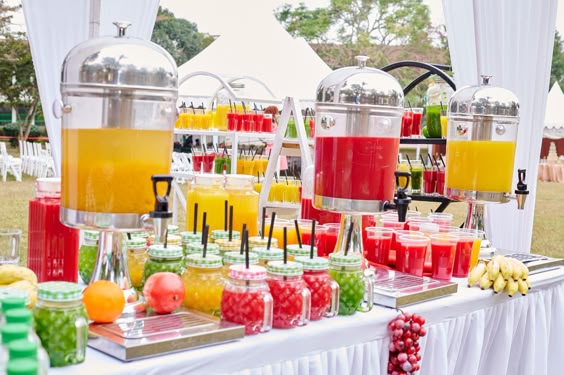 A vibrant juice and mocktail station set up at an outdoor wedding, offering inspiration for Kerala wedding menu ideas.