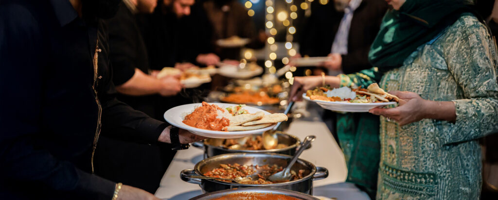 A buffet service featuring multiple regional and international dishes being served by guests, highlighting a well-planned multicultural wedding menu.