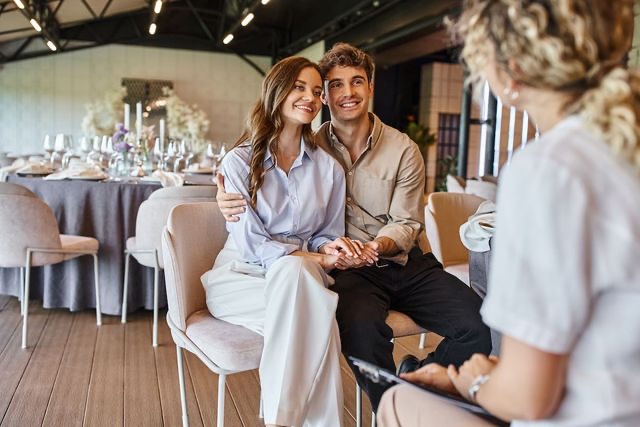 A bride and groom discussing wedding arrangements in a contemporary reception space, showcasing inspiration from the latest wedding catering trends.