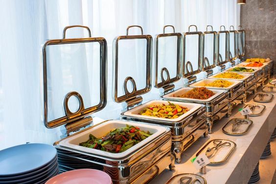 Elegant buffet-style setup with chafing dishes highlighting indoor vs outdoor wedding catering in Kerala, showcasing organised food presentation, hygiene standards, and guest flow management.