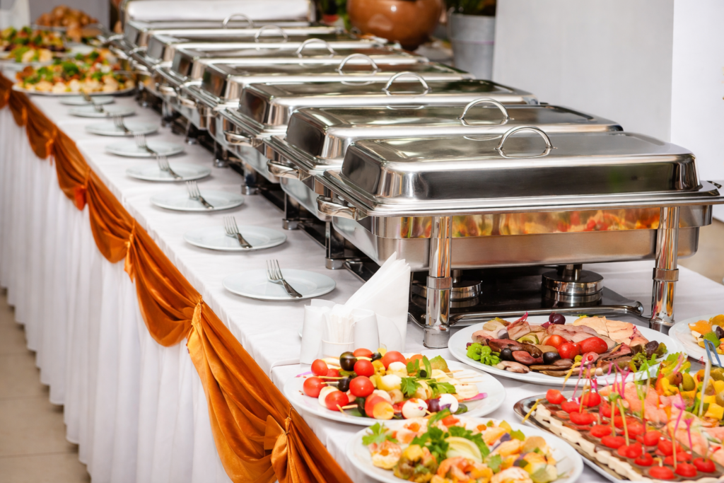 A classic wedding buffet setup with hot dishes and appetisers served in chafing trays, showcasing a traditional wedding menu Kerala.