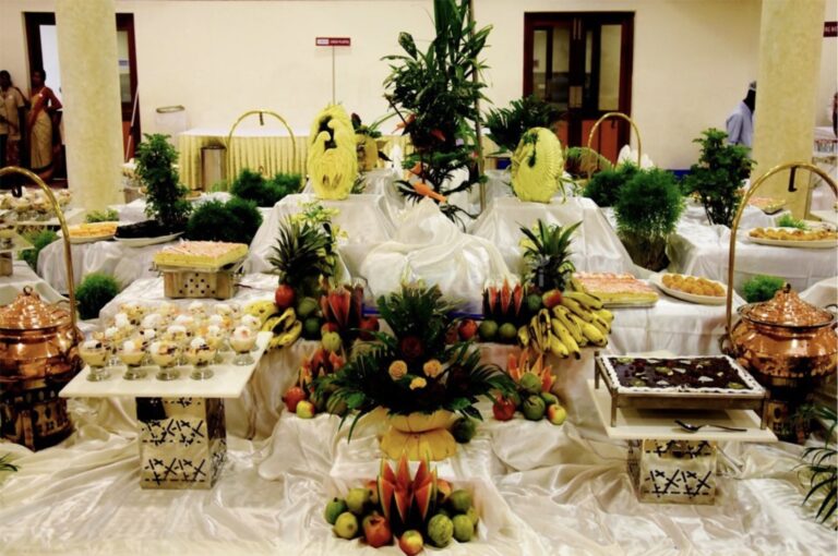 A beautifully arranged wedding buffet featuring traditional fruit carvings, sweets, and decorative food counters, highlighting premium wedding catering services in Kerala.