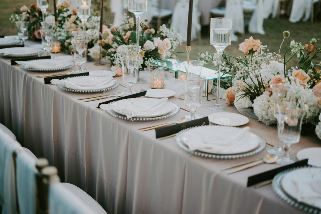 Sophisticated outdoor wedding dining setup with coordinated floral arrangements and fine table styling, showcasing premium wedding caterers in Kerala.